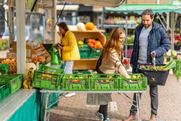 Junges Pärchen kauft auf dem Wochenmarkt ein